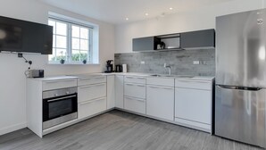 Una cucina moderna con mobili bianchi, un frigorifero in acciaio inossidabile e un forno integrato.