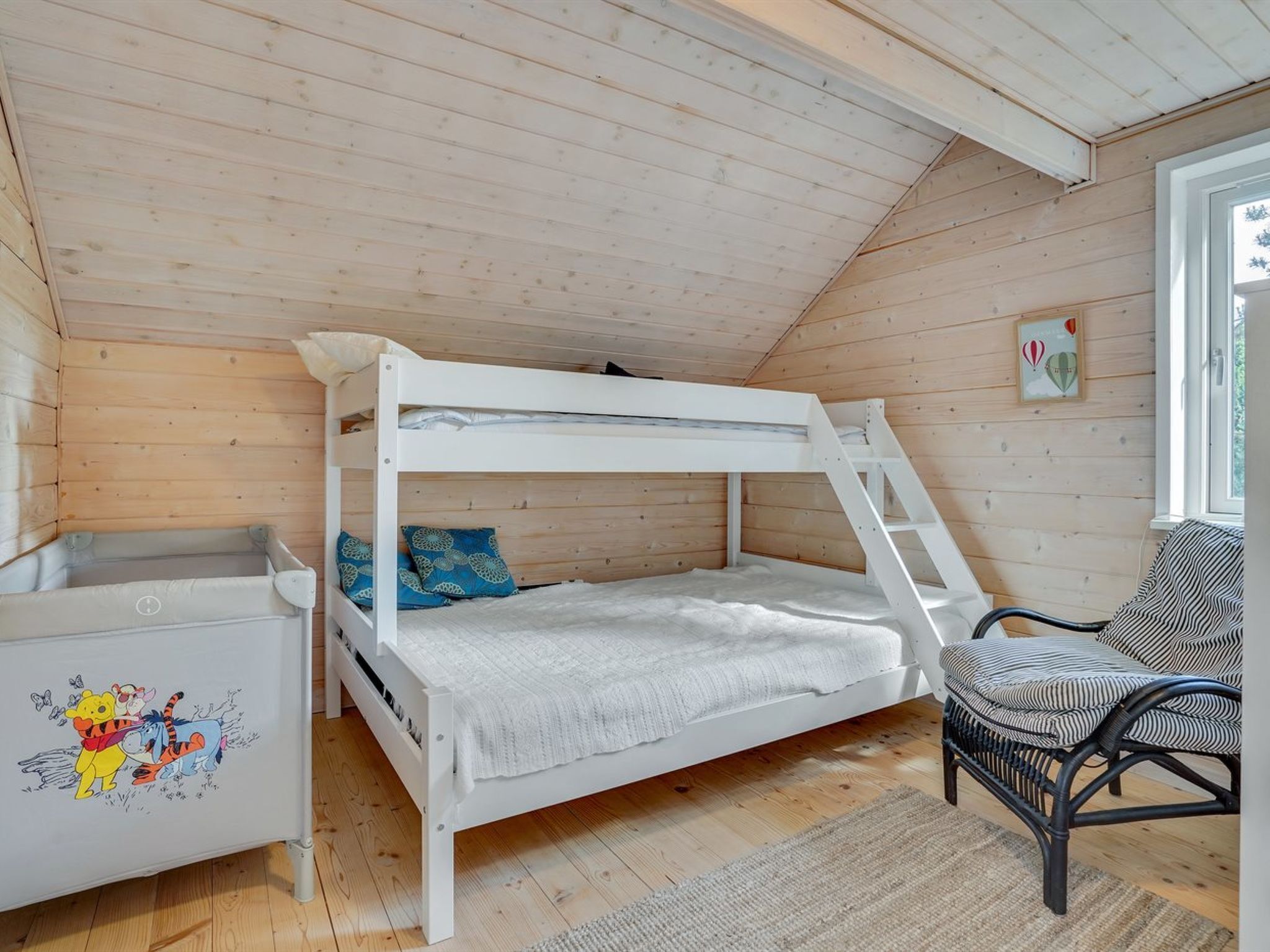 Een stapelbed met een ladder, een stoel en een klein tafeltje met een Winnie the Pooh dessin.