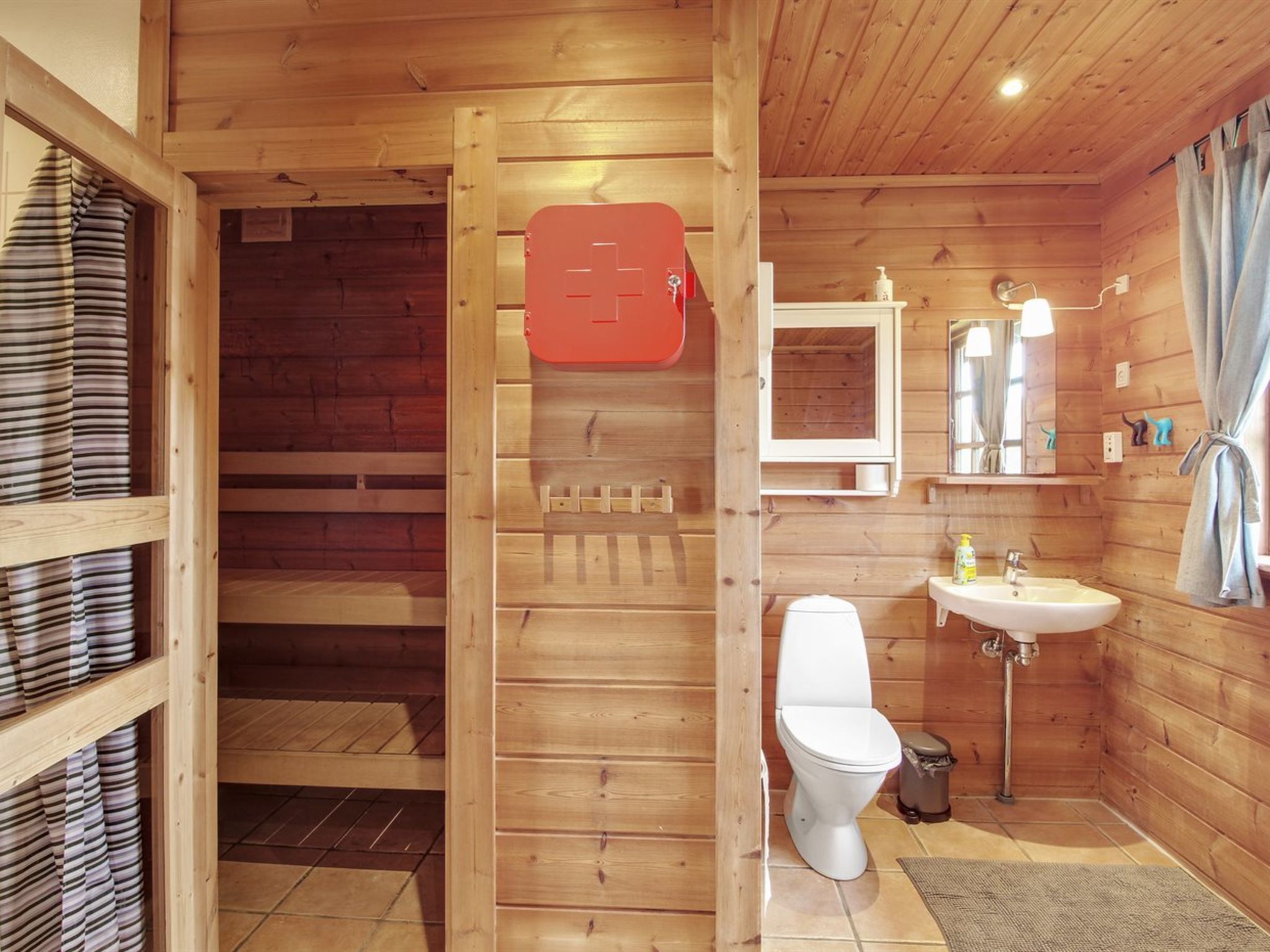 Baño de cabaña de madera con inodoro, lavabo y ducha.
