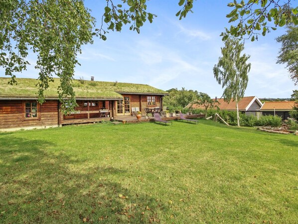 A wooden cabin with a deck and outdoor seating area.