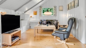 Una sala moderna con televisor de pantalla plana, un sofá, una mesa de centro y una silla.