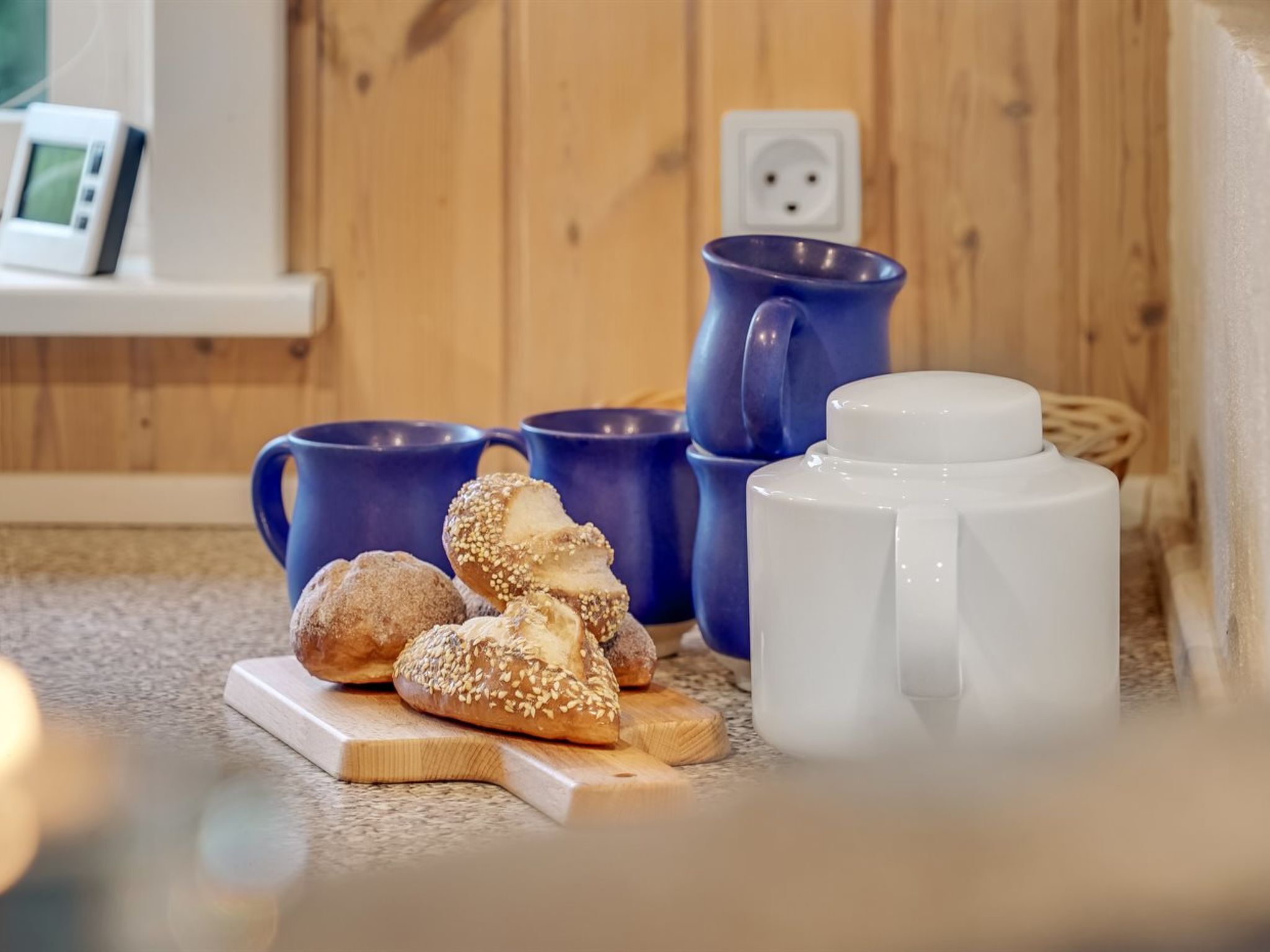 A kitchen area with a wooden floor, a white countertop, and a blue mug.