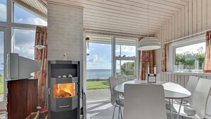 A modern interior with a fireplace, dining area, and large windows offering ocean views. - "Keti" - 5m from the sea by Interhome (Nyborg)