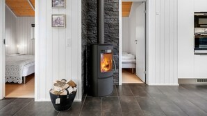 A modern interior with a stone wall, a wood-burning stove, a bed, and a dining area. - "Ketilbiorn" - 1.2km to the fjord by Interhome (Hemmet)