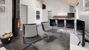 A modern interior with a fireplace, black leather chairs, a dining area, and a kitchen. - "Ketilbiorn" - 1.2km to the fjord by Interhome (Hemmet)