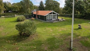 Een huis met een omheinde tuin, een terras met tuinmeubilair en een schommel.