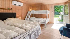 Een kamer met houten wanden en plafond, een stapelbed, een enkel bed, een bureau en een stoel.