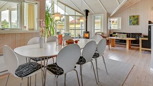 Een moderne eetruimte met een ronde tafel, witte stoelen en een centraal geplaatste open haard.