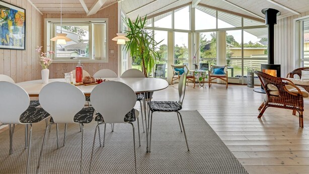 Een ruime eethoek met een hoge plafond, grote ramen en een centrale tafel met stoelen.