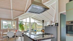 Een moderne keuken met een centraal eiland, grote ramen en uitzicht op de omgeving.