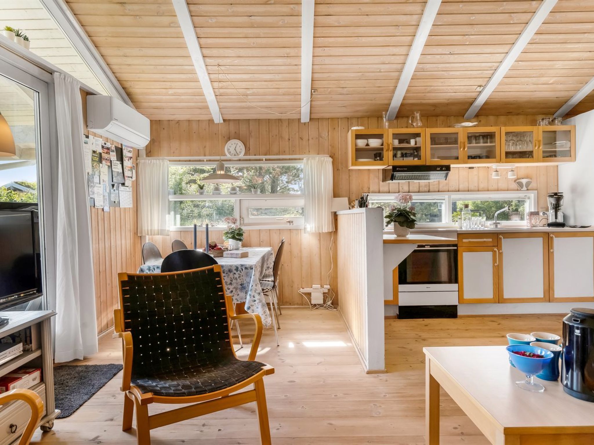 Une cuisine de taille réduite avec des meubles en bois, un coin repas comprenant une table et des chaises, et un téléviseur placé dans un coin.