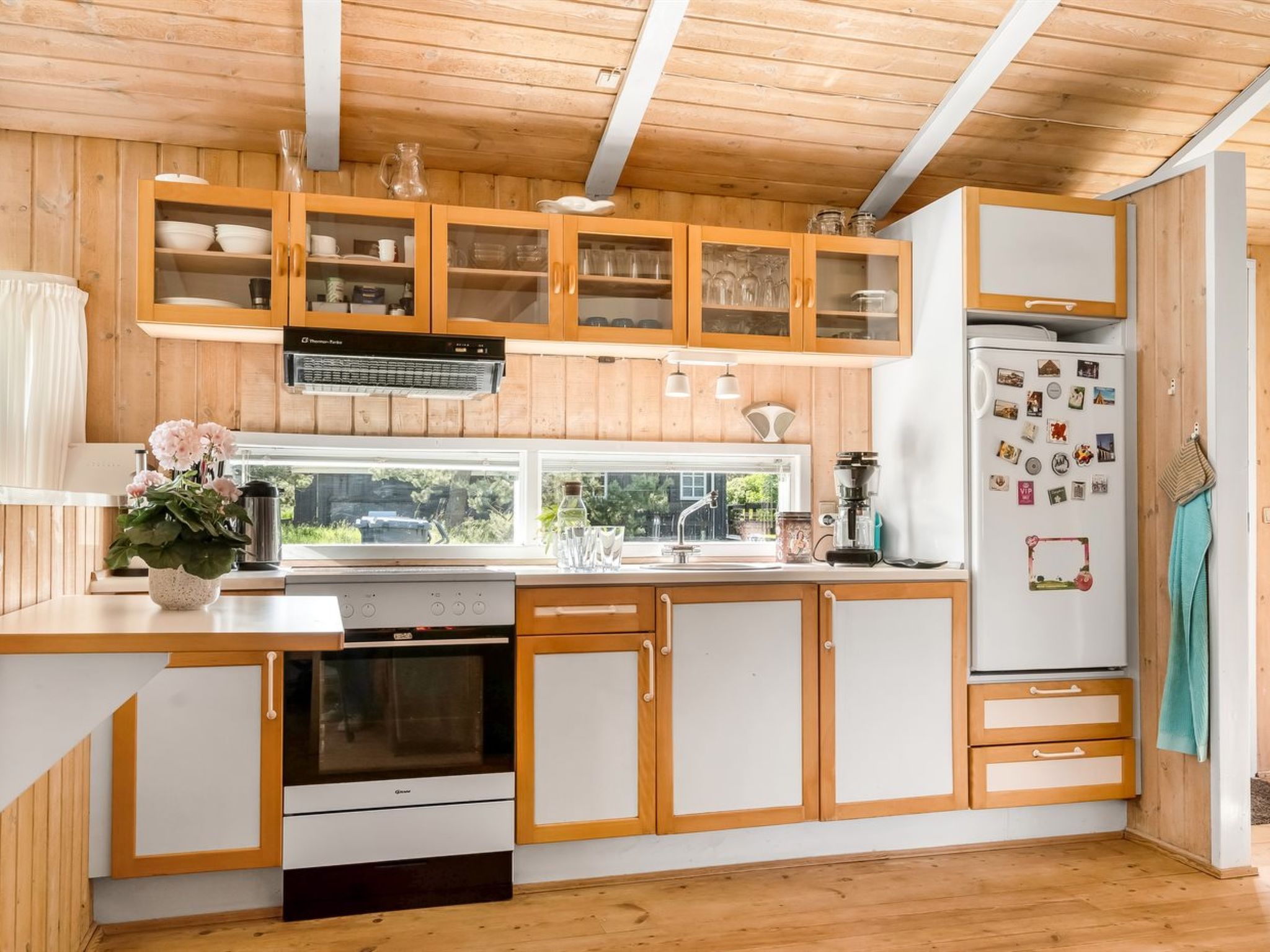 A modern kitchen with wooden cabinets, a built-in oven, and a refrigerator.