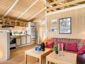 A cozy cabin interior with wooden walls, a kitchen area, a dining table, and a sofa. - "Anthonia" - 1.6km from the sea by Interhome (Blokhus)