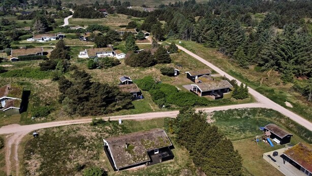 Luchtbeeld van een landelijk gebied met verspreide huizen, dicht bos en een helder uitzicht op de oceaan.