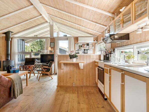 A spacious kitchen with wooden cabinets, a central island, and a dining area with a TV.