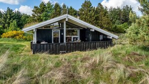 Een houten hut met een schuin dak, grote ramen en een terras.