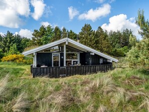 A wooden cabin with a sloped roof, large windows, and a deck area.