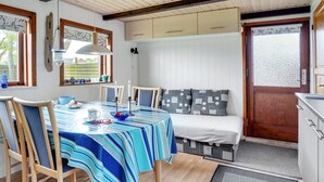 Une pièce chaleureuse avec une table à manger, des chaises, un canapé et un plafond en bois.
