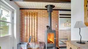 Une cuisine moderne avec un poêle à bois, un mur en briques et des poutres en bois au plafond.