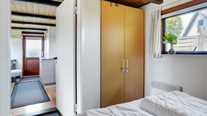 Une chambre à coucher avec une armoire en bois, un lit et une fenêtre donnant sur l’extérieur.