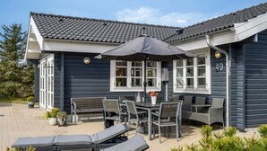 A house with a patio area featuring a table, chairs, and a large umbrella.
