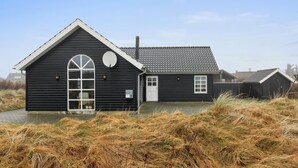 En sort bygning med tagkviste, et stort buet vindue og en parabol.