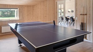 Une table de ping-pong dans une pièce aux murs en bois et dotée d’une fenêtre.