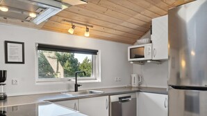 Une cuisine moderne dotée d’un plan de travail en granit, d’appareils électroménagers en acier inoxydable, d’une fenêtre offrant une vue agréable et de poutres en bois au plafond.