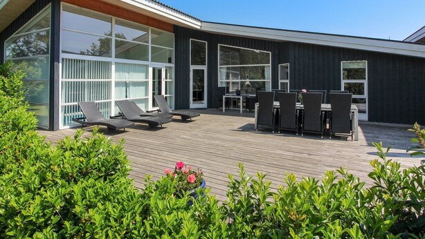 Een modern huis met een groot terras, buitenmeubels en een glazen patio.
