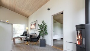 Een moderne woonkamer met een open haard, houten vloeren, een bank, een salontafel en een plant in een pot.