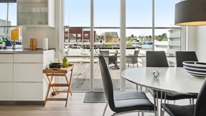 Una cocina moderna con un amplio ventanal, un comedor con mesa redonda y vistas a un puerto deportivo.