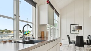 Una cocina moderna con un ventanal grande, un lavamanos empotrado y una zona de comedor con mesa y sillas.