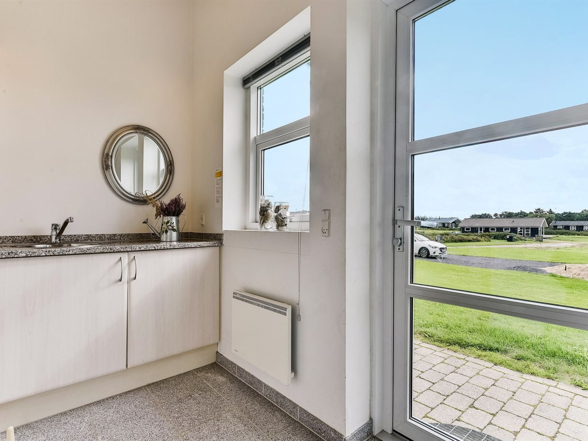 A modern bathroom with a large window, a sink, a mirror, and a radiator.