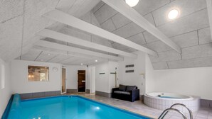 Une piscine intérieure avec un jacuzzi, un canapé et une porte donnant sur une autre pièce.