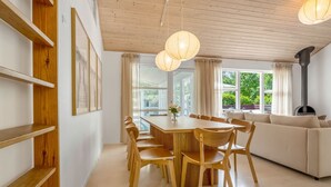 A modern interior with a wooden dining table, chairs, a sofa, and a fireplace.
