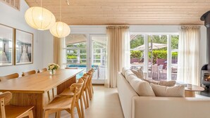 A modern interior with a wooden dining table, chairs, a sofa, and a fireplace. - "Börje" - 600m from the sea by Interhome (Væggerløse)