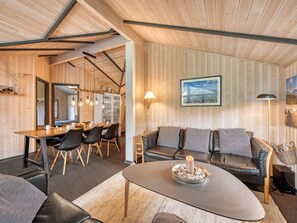 Un interior moderno con comedor, un conjunto de sofás y una chimenea.
