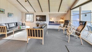 Una sala de estar acogedora con un sofá, una mesa de centro y un televisor. Hay una cama con ventana y una silla con vistas.