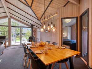 A modern dining area with a wooden table set for four, surrounded by chairs.
