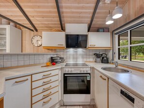 A modern kitchen with white cabinetry, a built-in oven, a sink, and a window providing a view of the outdoors. - "Martina" - 560m to the fjord by Interhome (Hemmet)