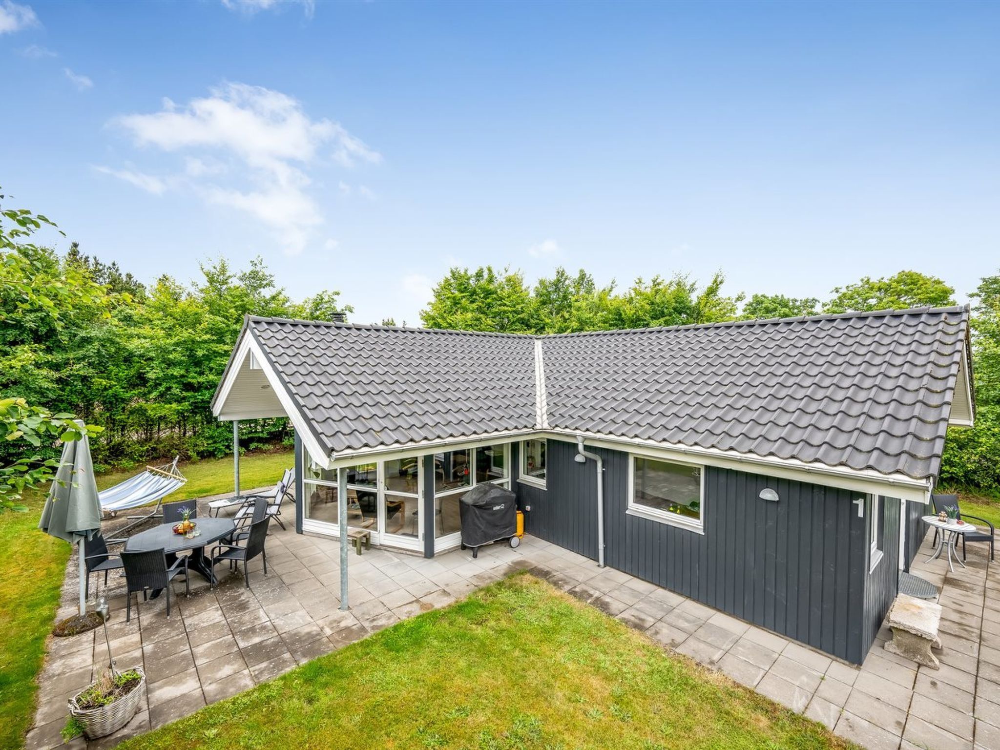 Une maison moderne dotée d’un patio couvert, d’un barbecue et d’un coin repas.