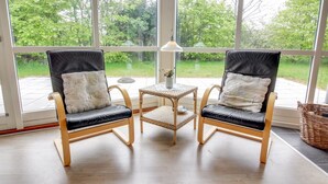 Deux fauteuils en cuir noir avec des coussins blancs, une petite table en osier et un lampadaire.