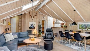 A spacious loft with a high ceiling, wooden walls, a dining area, and a cozy seating area with a sofa and ottoman. - "Anastaja" - 12km from the sea by Interhome (Oksbøl)