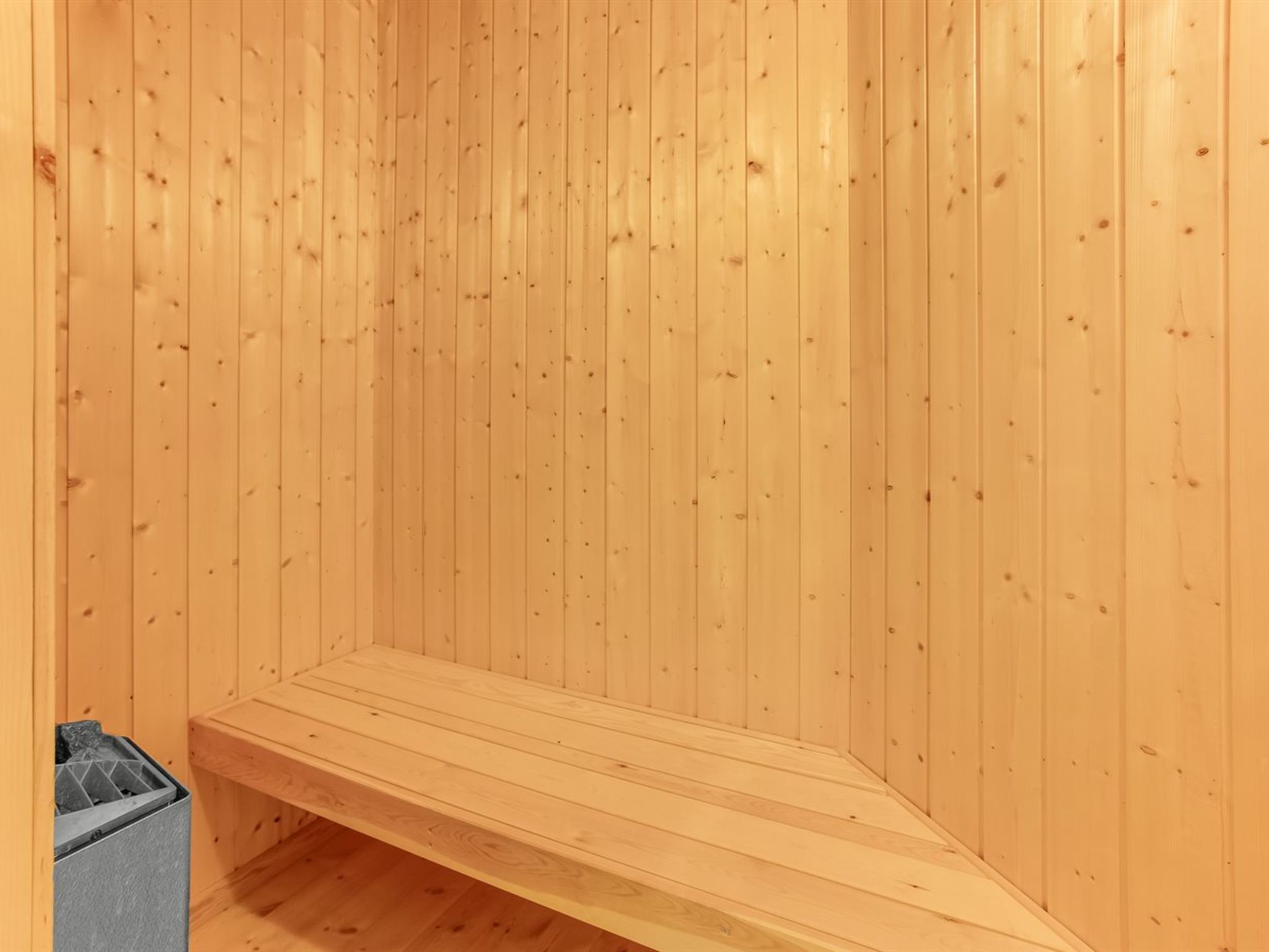 A wooden sauna with a bench and a trash bin.