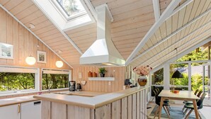 A modern kitchen with wooden walls, a central island, and a dining area with a table and chairs. - "Anastaja" - 12km from the sea by Interhome (Oksbøl)