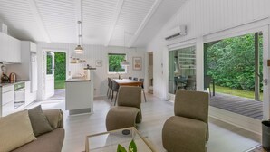 Een modern interieur met een eetgedeelte, keuken en zithoek met uitzicht op groen.