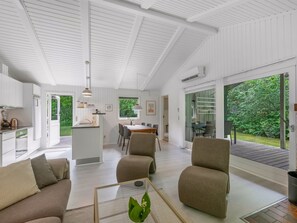 Un intérieur moderne comprenant un coin repas, une cuisine et un espace détente avec vue sur la verdure.