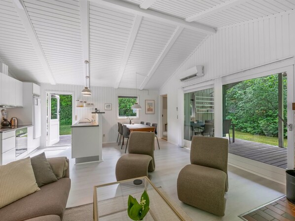 Un interior moderno con comedor, cocina y zona de estar con vista a la vegetación.