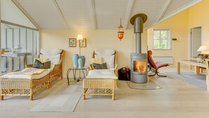 Una habitación acogedora con muebles de mimbre, chimenea y un ventanal grande.