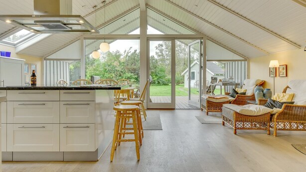 Una cocina amplia con una isla grande, sillas de madera y un comedor con mobiliario de mimbre.